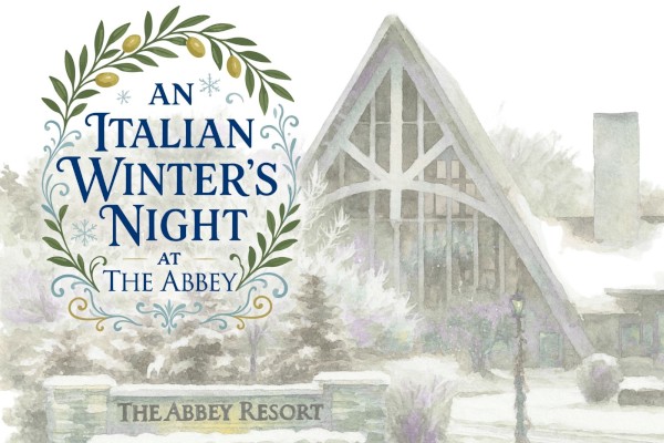 A winter scene at An Italian Winter's Night event sign, with a glassy logo and a rustic entrance to The Abbey Resort, in snowfall.