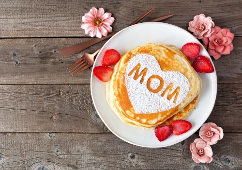 A stack of pancakes with a heart-shaped powder sugar design and the word 