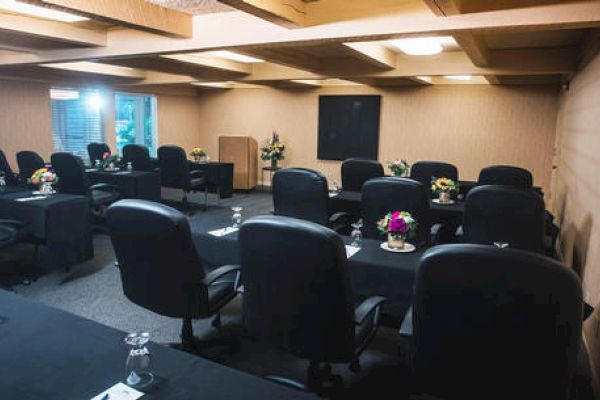 This image shows a conference room set up with black chairs around tables, each adorned with flowers and conference materials, ending the sentence.