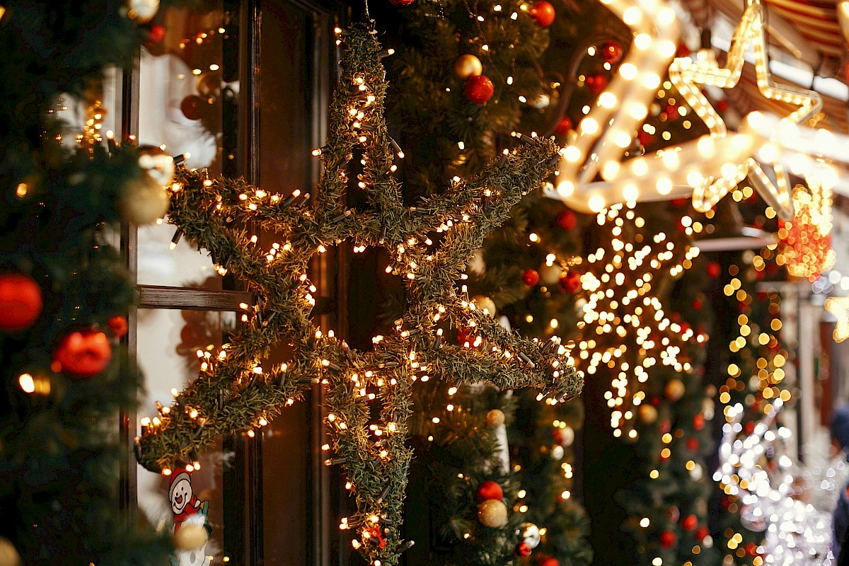 Christmas decorations with lights, stars, and ornaments on a festive street at night.