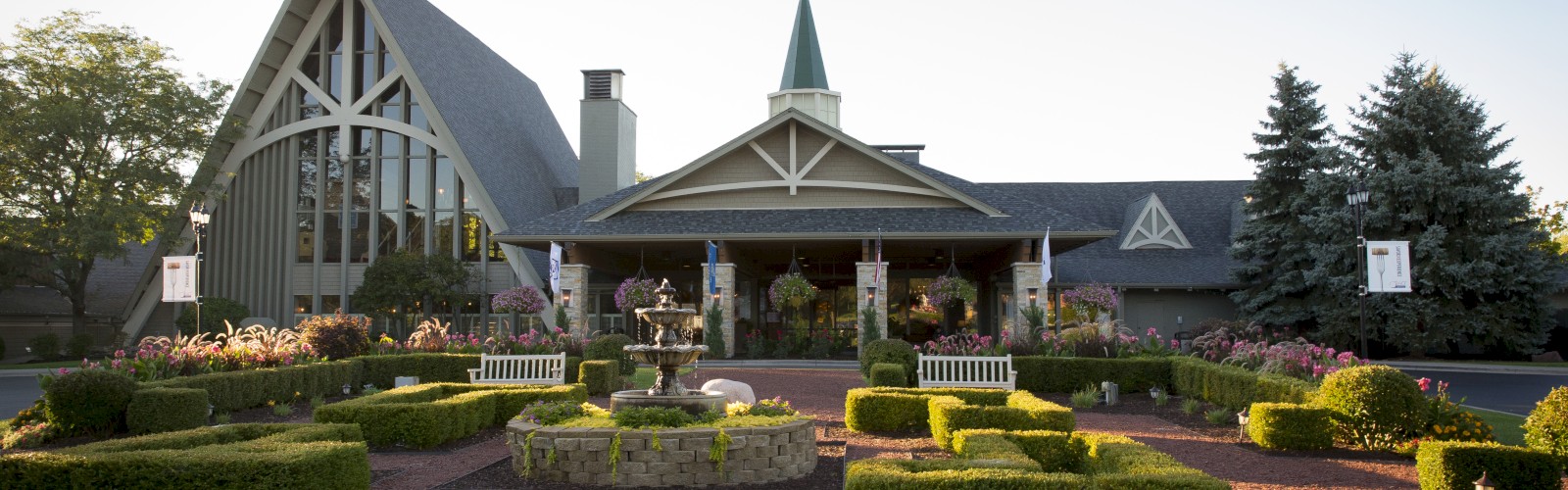 The image shows a beautifully landscaped garden with a water fountain in front of a building that resembles a church or chapel.