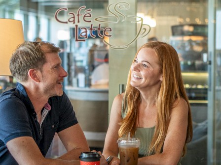 A man and woman sit happily at a café, enjoying drinks together, with 