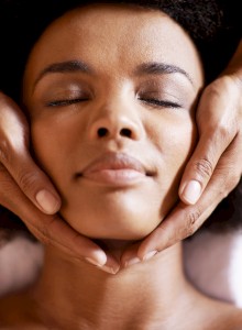 A close-up portrait of a person with a serene expression, hands gently cradling their face, highlighting calm self-care.
