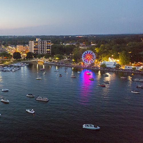 An aerial view of a coastal town at dusk, showcasing a harbor with boats, a pier, and a colorful Ferris wheel in the background, ending the sentence.