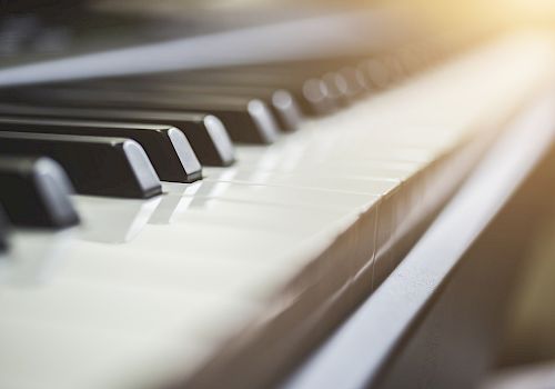 A close-up shot of piano keys with sunlight shining on them, showing a detailed view of the black and white keys.