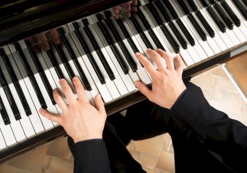 A person playing a piano, focusing on their hands on the keys.