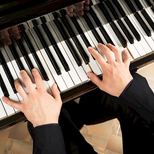 A person playing a piano, focusing on their hands on the keys.