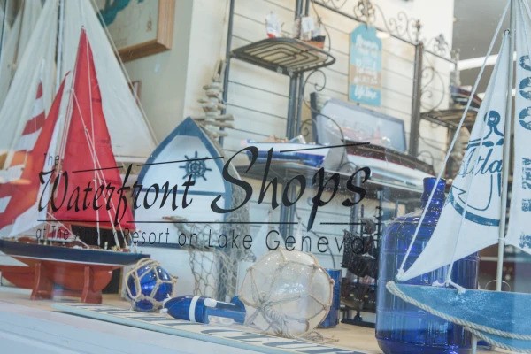 The image shows a shop window displaying nautical-themed decor, with sailboats and marine items. The text reads 
