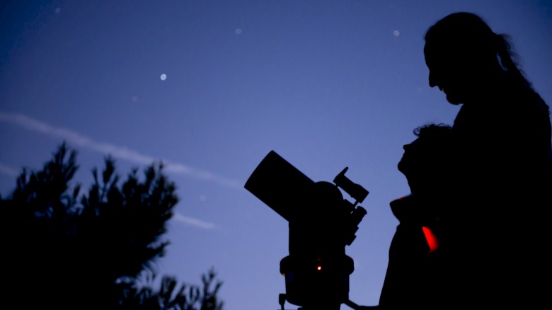 People are watching the night sky, using a telescope to observe the stars and planets.