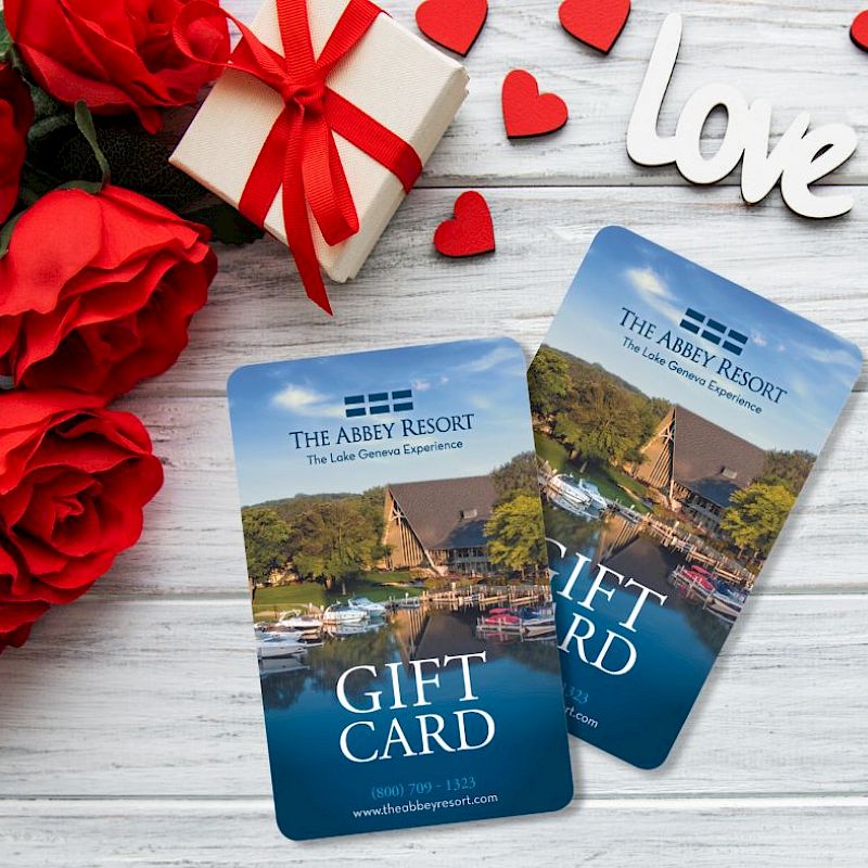 Image of two gift cards for The Abbey Resort, surrounded by red roses, a present, and heart decorations with 