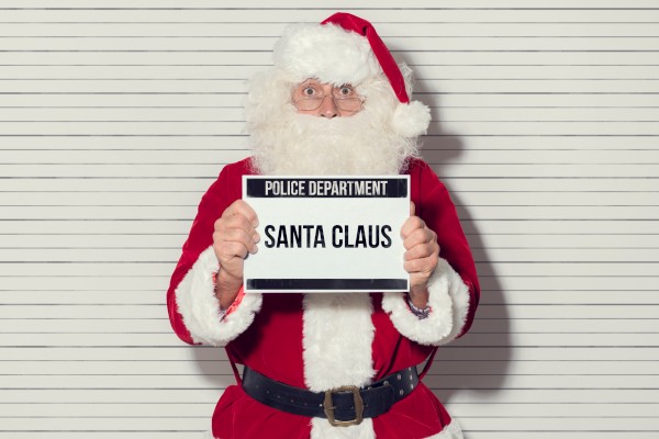 A person in a Santa Claus costume is holding a sign that reads 
